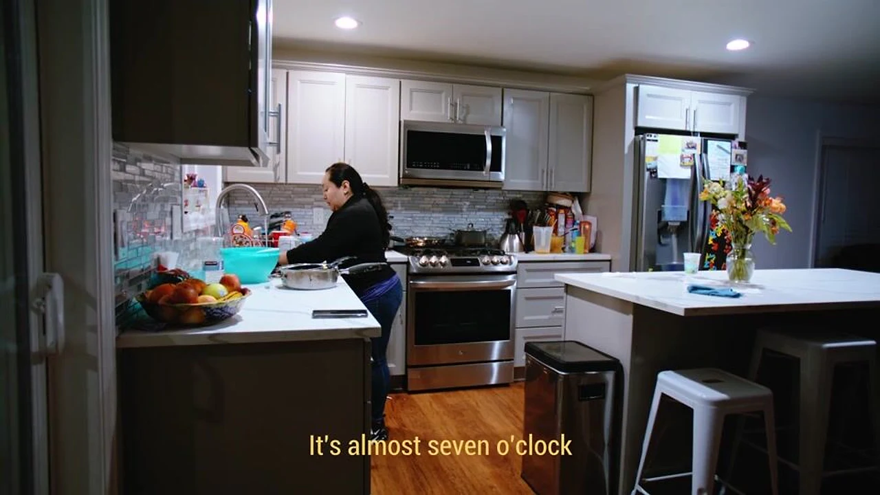 A woman prepares food in a bright home kitchen during a documentary scene