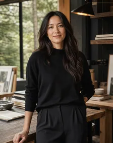 A woman in black stands in a warm, wood-paneled office