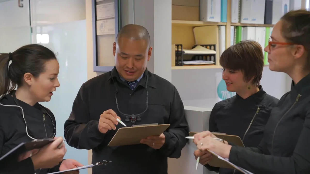 Dr. Benjamin Wang and members of his dental team review clipboards