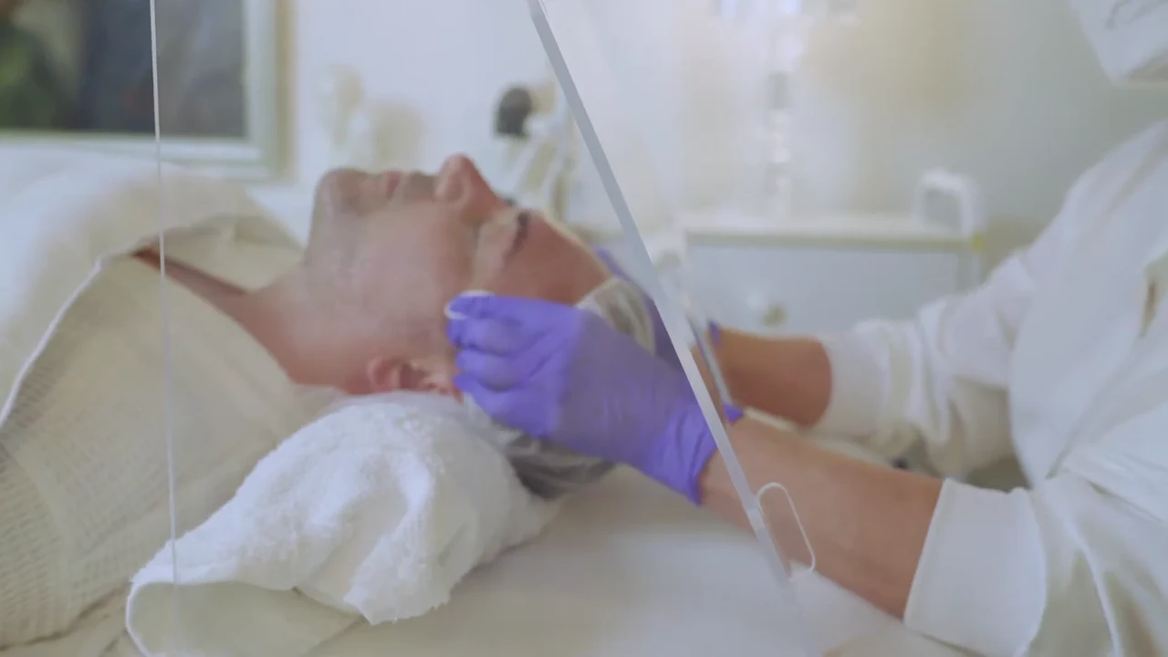 A clinician wearing gloves demonstrates an aerosol barrier during treatment