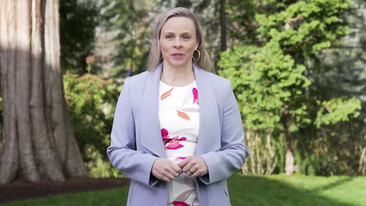 Realtor Korrie Hicks speaks outdoors in a wooded setting